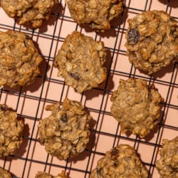 oatmeal raisin cookies on wire cooling rack set above a peach coloured background