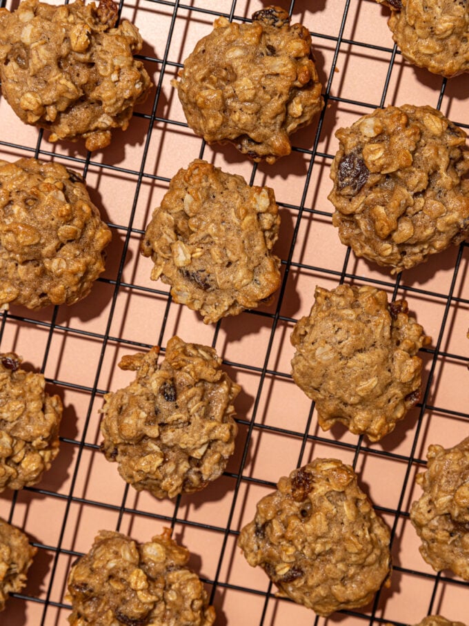 oatmeal raisin cookies on wire cooling rack set above a peach coloured background