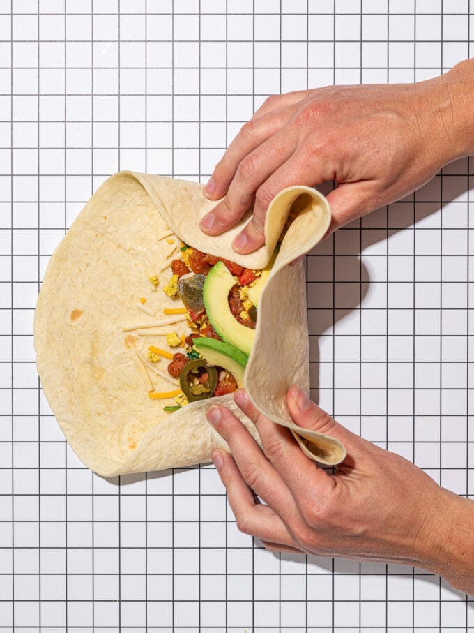 hand folding and wrapping a tofu breakfast burrito