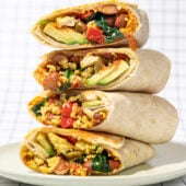 stack of 4 tofu breakfast burritos with avocado, spinach and red pepper on a white plate