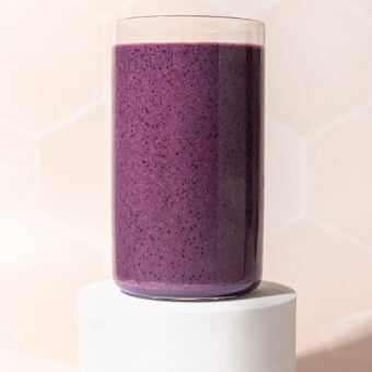 glass of blueberry beet smoothie on white pedestal