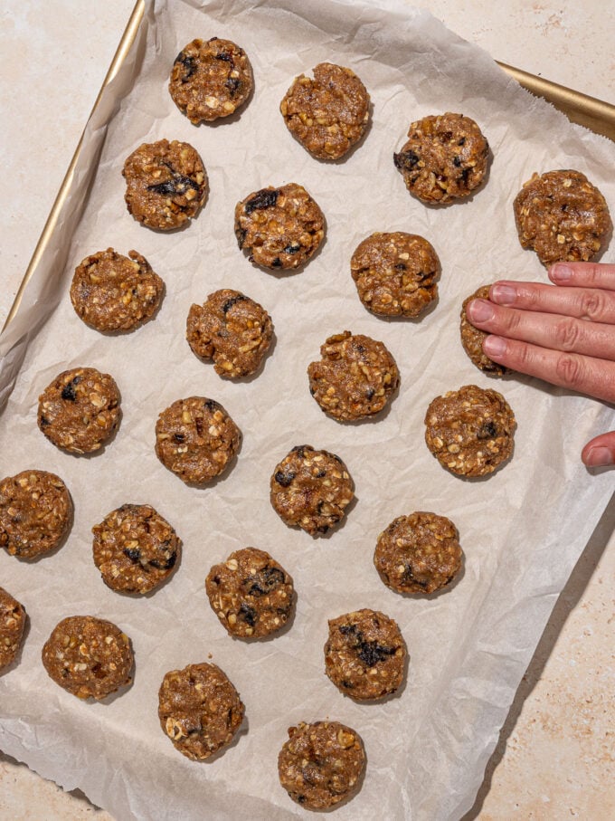 hand pressing down raw prune cookies