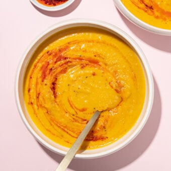 white bowl filled with butternut squash soup that's been swirled with a bit of chili oil