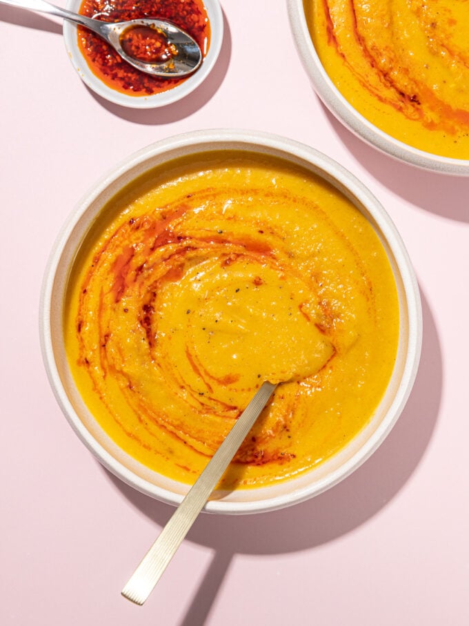 white bowl filled with butternut squash soup that's been swirled with a bit of chili oil
