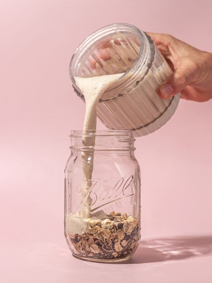 hand pouring milk into mason jar with oats, chia and chocolate chips