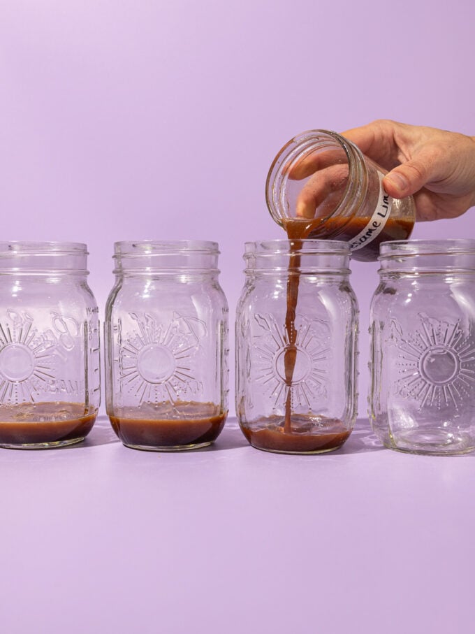 hand pouring dressing into 4 glass jars
